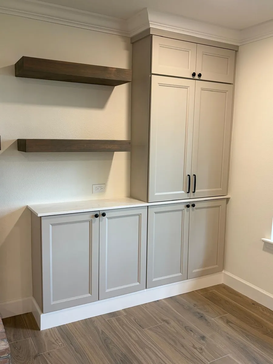 White cabinets with floating wood shelves in a finished room