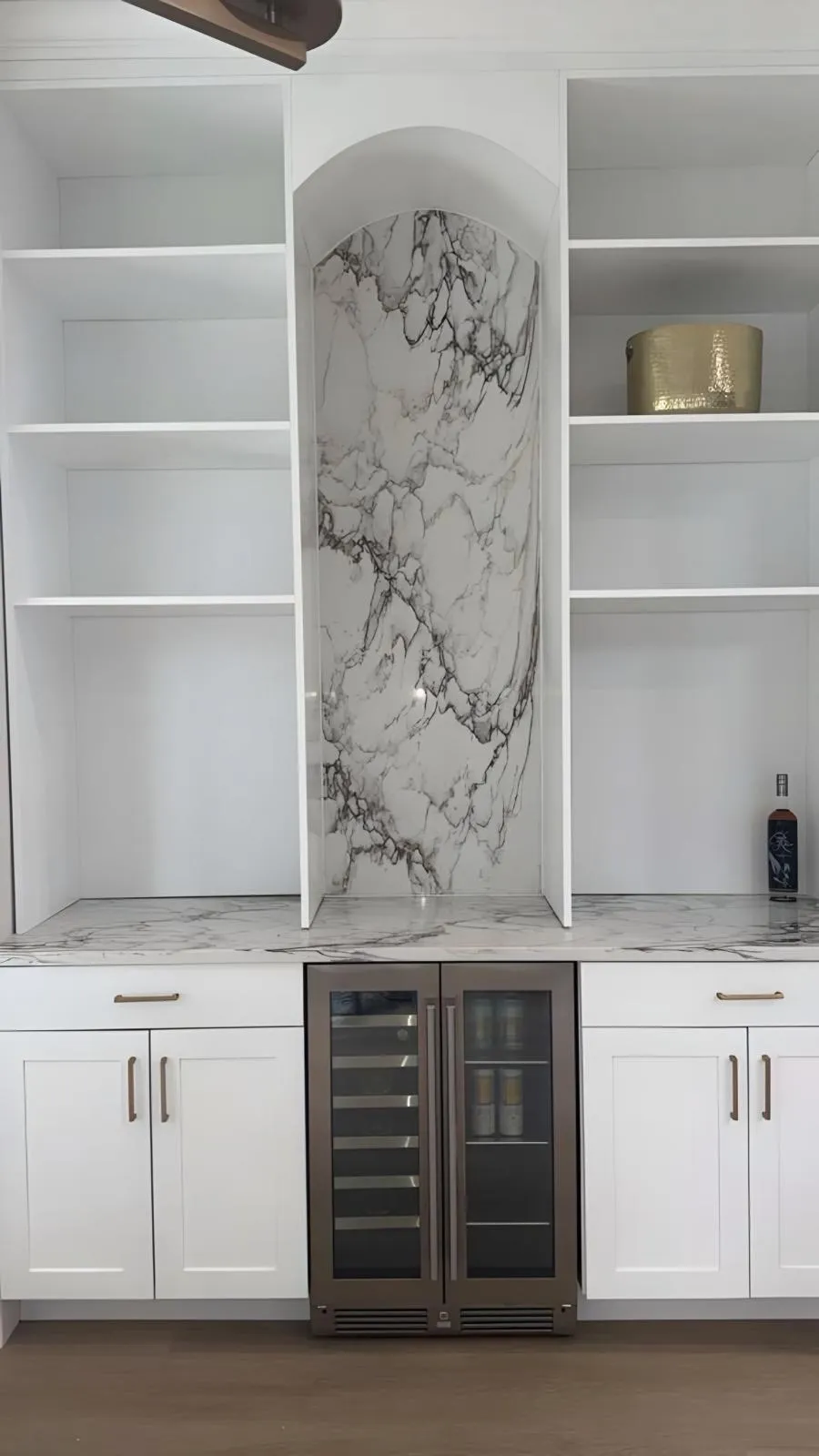 Built in bar with a stone panel in the arch niche and a wine cooler