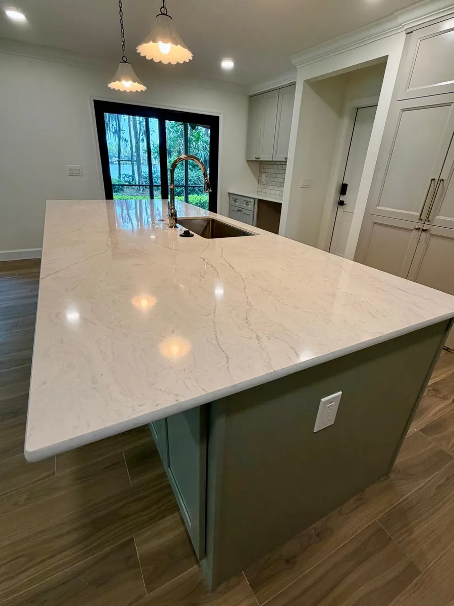 Kitchen island with a painted base and a light stone top with a mitered edge