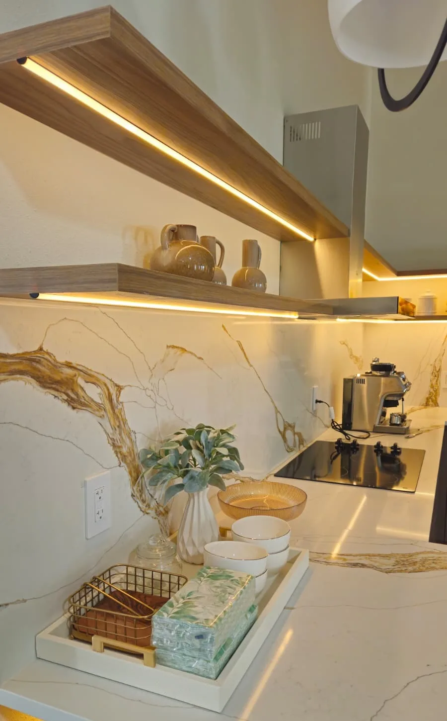 Full stone slab backsplash with gold veining behind a cooktop