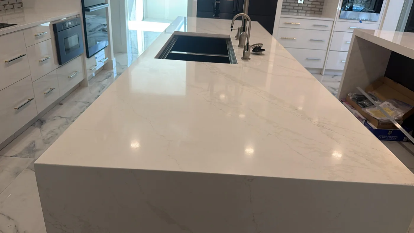 Kitchen island with a light engineered stone top and a polished edge