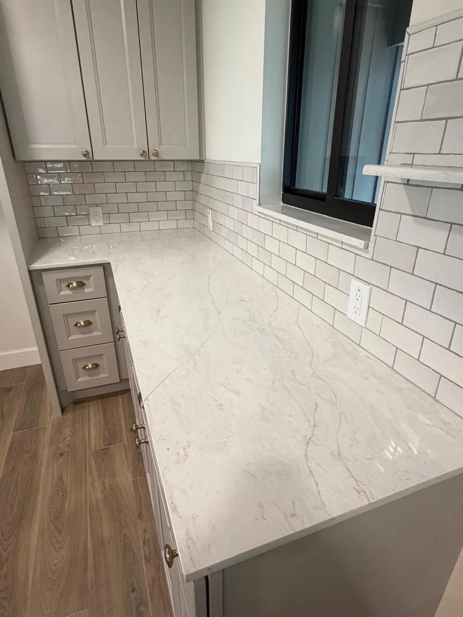 Kitchen counter run with a subway tile wall and a light stone top